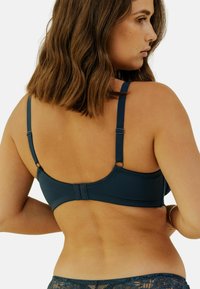 Soutien-gorge bleu foncé avec bretelles réglables, présentant une texture de tissu lisse et une fermeture à crochet et œillet. Détails en dentelle en bas.