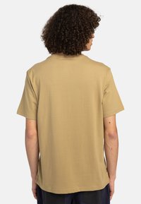 Beige T-Shirt mit kurzen Ärmeln aus weichem Baumwollmix. Mit Rundhalsausschnitt, lockerer Passform und Etikett an der linken Seitennaht.