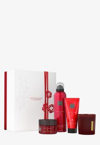 Presentset med vit ask prydd med röd blommönster och band. Innehåller fyra röda produkter: kroppsskrubb, kroppskräm, duschskum, ljus.