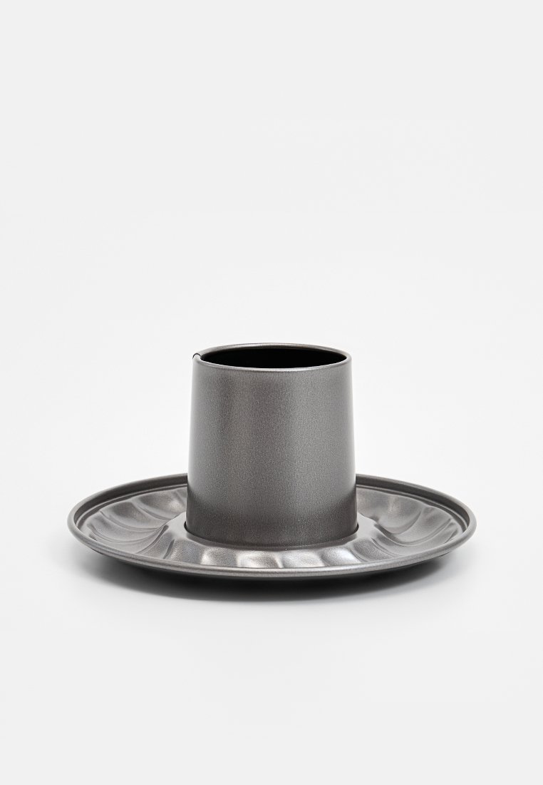 Szara ceramiczna filiżanka o gładkiej powierzchni, umieszczona na pasującym talerzyku z falistymi brzegami, ukazująca nowoczesny i minimalistyczny design.
