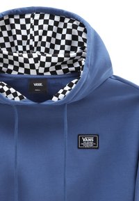 Niebieska bluza z kapturem z czarno-białą kratowaną podszewką, z naszywką z logo na przodzie. Wykonana z miękkiego materiału o klasycznym kroju.