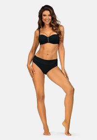 Czarny zestaw bikini z topem bandeau, który ma trzy metalowe pierścienie na środku oraz wysokim stanem majtek. Gładki materiał, minimalistyczny design.