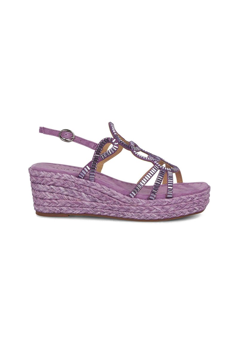 Sandalia de cuña morada con suela de yute trenzada, intrincadas correas trenzadas y acentos decorativos. Incluye una correa ajustable en el tobillo.