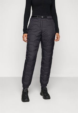 Pantalons d'extérieur noirs rembourrés avec une taille élastique et des poignets, présentant une texture matelassée avec des coutures verticales et une ceinture.