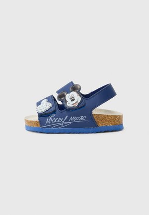 Sandales bleues avec deux sangles réglables, dotées d'un design Mickey Mouse et d'une semelle en liège. Les détails notables incluent un graphique de pouce levé et un logo.