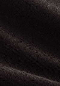 Tissu texturé marron foncé avec un motif tissé fin et des reflets lumineux doux créant de légers plis.