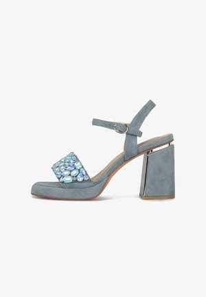 Blaue Wildleder-Sandalette mit Blockabsatz, Knöchelriemen mit Schnalle und großen reflektierenden Edelsteinen auf dem vorderen Riemen.