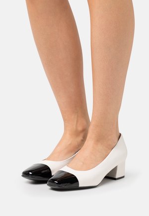 Deux escarpins à talons en bloc, avec un corps en cuir blanc et des bouts en cuir verni noir brillant. Bout rond et texture lisse, offrant un design classique.