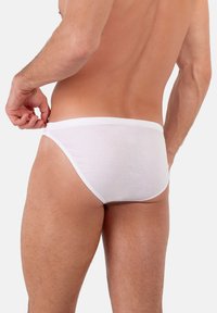 Slip bianchi da uomo realizzati in cotone morbido. Presentano un design a vita bassa, una cintura elastica e una texture liscia. Visti da dietro.