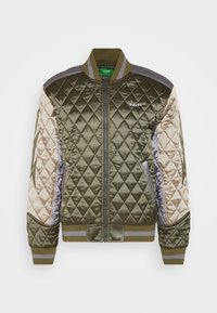 Veste bomber en satin matelassé vert olive avec manches beige, col et poignets côtelés, poches avant et logo "huf" sur la poitrine gauche.