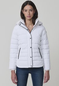 Chaqueta acolchada blanca con capucha, ribetes negros y botones a presión. Presenta costuras verticales y dos bolsillos laterales. Tejido suave e insulated.
