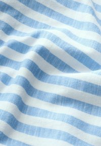Tessuto morbido con righe orizzontali azzurro chiaro e bianco che creano pieghe e ombre delicate.