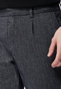 Ciemnoszare spodnie z denimu, z subtelnym teksturowanym wzorem, kieszeniami bocznymi i dopasowanym krojem, z płaskim stanem i szlufkami na pasek.