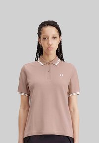 Polo a maniche corte in rosa polveroso con strisce bianche a contrasto sul colletto e sui polsini, con un piccolo logo sul petto.