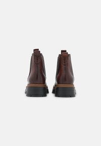 Bruna läder chelsea-boots med en staplad klack, elastiska sidopaneler och dragflikar. Har svarta gummisulor och en slät yta.