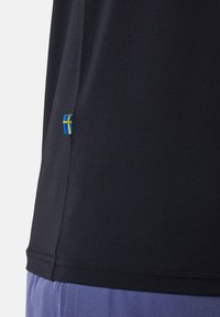 Zwart atletisch shirt met een ademende textuur, voorzien van een kleine blauw-geel Zweedse vlag genaaid aan de zoom.