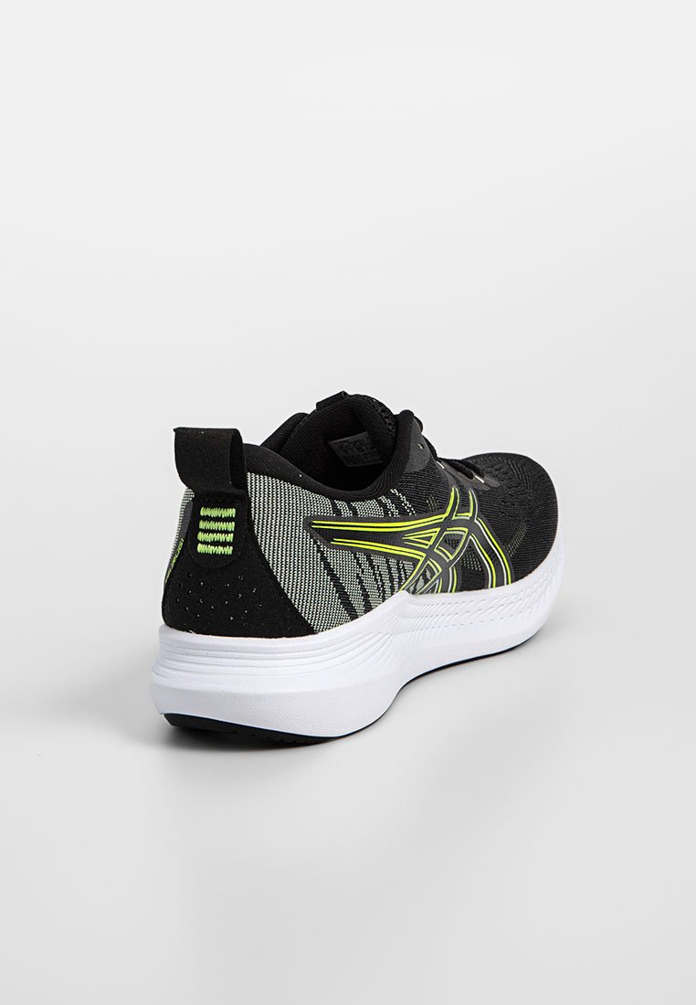 Zapatilla deportiva negra y verde neón con suela blanca, parte superior de punto, lenguaje de agarre, y patrón geométrico sobre un fondo claro.