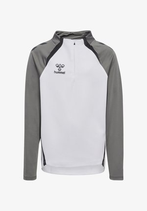 T-shirt de sport à manches longues en blanc avec des manches raglan grises ; il dispose d'un col à demi-zip et d'un logo noir sur le haut à gauche de la poitrine.