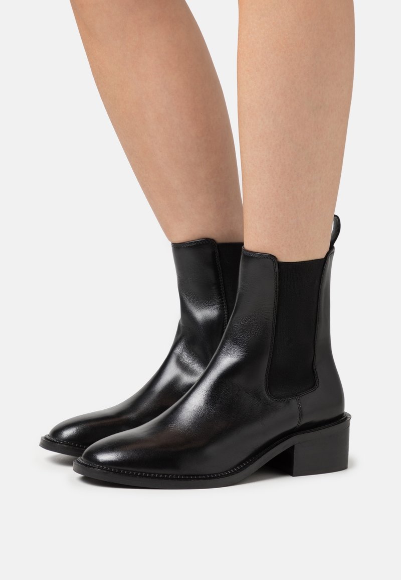 Botines de cuero negro con un acabado suave, paneles laterales elásticos, punta afilada y un tacón bajo en bloque.