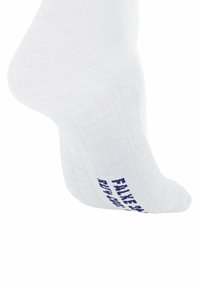 Biała bawełniana skarpetka o prążkowanej fakturze, z niebieskim napisem na boku. Kształt dopasowuje się do stopy, zapewniając ciasne dopasowanie.