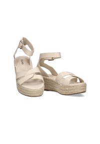 Sandalias de cuña beige con un diseño de tiras cruzadas, hebilla en el tobillo y plataforma envuelta en yute. Material superior sintético suave.