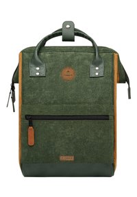 Zaino in corduroy verde con dettagli in pelle, un manico superiore, una tasca frontale con zip e una toppa circolare con logo. Presenta un fondo robusto.