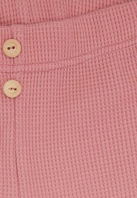 Tessuto a coste rosa con una superficie testurizzata, dotato di due bottoni in legno sulla vita e una cucitura pulita.