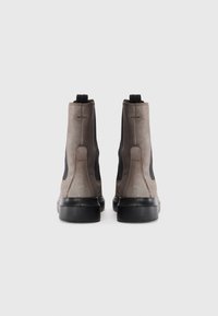 Botas altas con exterior de ante gris, paneles laterales negros y suelas de goma texturizadas. Cuentan con lengüetas en el talón para ponérselas fácilmente.