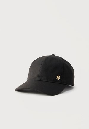 Gorra de béisbol negra con visera curva y pequeño logo metálico dorado en el lateral, exhibida sobre superficie blanca.