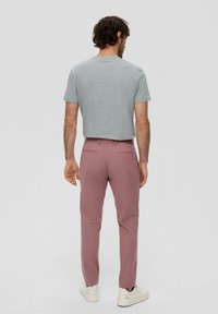Grijze T-shirt met korte mouwen gecombineerd met lichtroze pantalon en witte sneakers, gezien vanaf de achterkant. Zacht materiaal, getailleerd ontwerp.