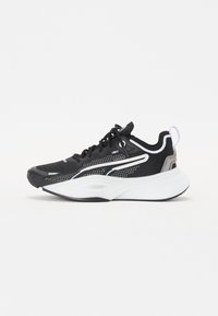 Scarpa sportiva nera con tomaia in rete testurizzata, accenti bianchi, suola spessa e dettagli riflettenti. Presenta tradizionale chiusura con lacci.