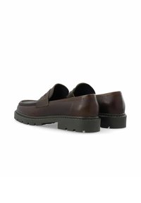 Mocassins en cuir marron avec une finition texturée, détail de sangle rectangulaire et semelle en caoutchouc noir robuste pour une adhérence accrue.