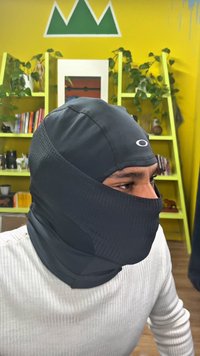 Musta elastisesta materiaalista valmistettu balaclava, jossa on teksturoitu kuvio ja Oakleyn logo otsan alueella.