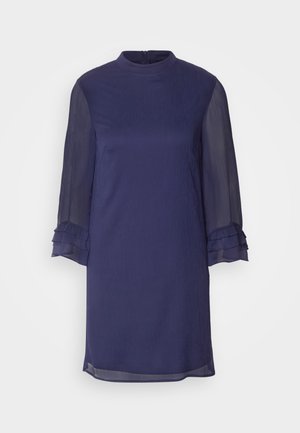 Rochie bleumarin cu guler înalt, mâneci lungi din material transparent cu volane și croi drept. Textură de țesătură netedă, lungime deasupra genunchiului.