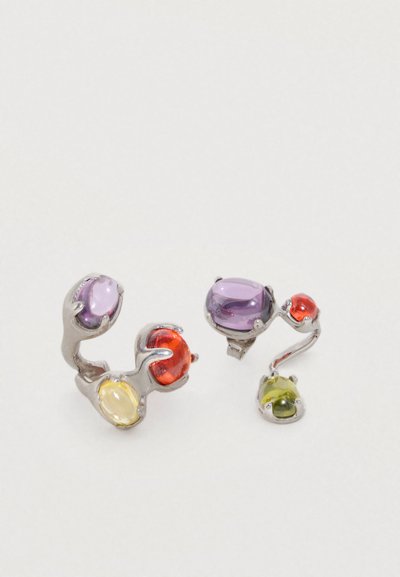 Bagues en pierres précieuses colorées avec des pierres taillées en ovale dans des tons violet, orange, jaune et vert, montées sur un métal argenté avec une forme torsadée.