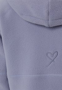 Lila Fleece-Hoodie mit strukturierter Oberfläche, ausgestattet mit einer herzförmigen Stickerei in einer kontrastierenden Farbe und sichtbaren Nahtdetails.