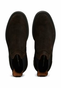 Musta ruskea mokkanahka nilkkaboots, joissa on joustavat sivupaneelit, teksturoitu pinta, pyöristetty kärki ja kontrastivärinen ompeleet.
