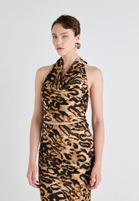 Halter-neck kjole i leopardmønster med bølgende halsringning, som har brune og sorte mønstre på en beige bakgrunn. Slim fit design.