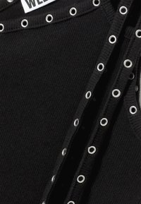 Μαύρο ριμπ τοπ με ασημένιες λεπτομέρειες από μεταλλικά τρουκ στα άκρα και ετικέτα που γράφει "WELL." Η υφή είναι λεία και εφαρμοστή.