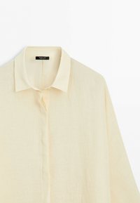 Cream-colored long-sleeve shirt with a classic collar and concealed button placket, displayed against a white background.