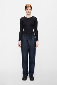 Czarna dopasowana bluzka z długim rękawem zestawiona z luźnymi granatowymi spodniami z wysokim stanem. Spodnie mają elastyczny pas i marszczone nogawki, wykonane z gładkiego materiału.