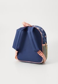 Pequena mochila azul marinho com alças rosas, frente estampada com flores, fecho de zíper e bolso lateral em malha bege, de pé sobre fundo branco.