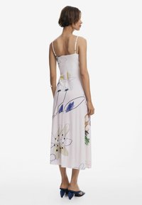 Midi-Spaghettiträgerkleid aus weichem rosa Stoff, mit bunten Blumenmustern und einer lockeren Silhouette mit einem Seitenschlitz.