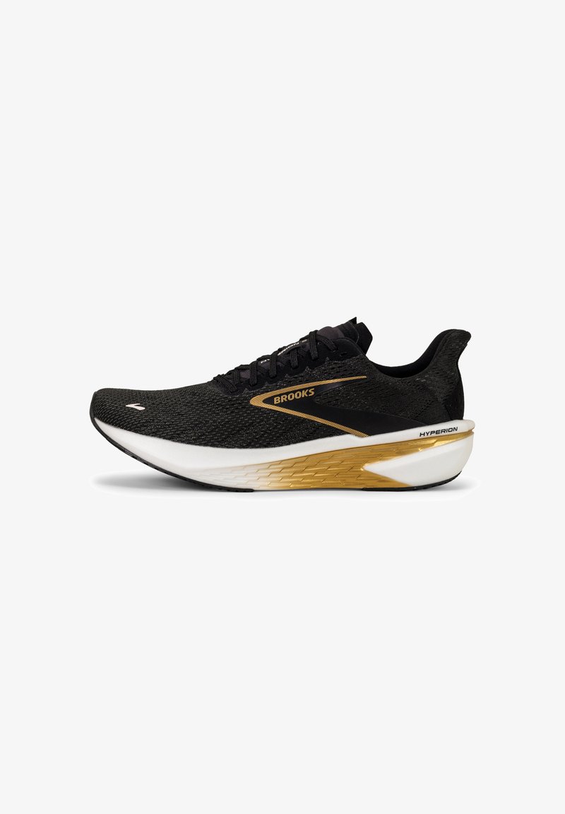 Zapatilla de running negra con parte superior de malla transpirable, detalles dorados, entresuela blanca y suela de goma. Presenta cordones planos y el nombre de la marca "Brooks."
