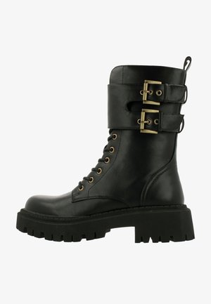 Stivaletto in pelle nera con lacci sulla parte anteriore, due cinturini con fibbia e una robusta suola in gomma nera con texture rigata.