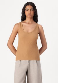 Top de tirantes marrón con un escote redondeado y un diseño ajustado, combinado con pantalones de pierna ancha en gris claro. Textura suave, estilo casual.