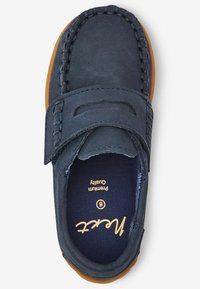 Scarpa blu navy con una consistenza morbida, dotata di una fascia in Velcro, dettagli cuciti e suola in gomma marrone. Internamente etichettata con taglia e marca.