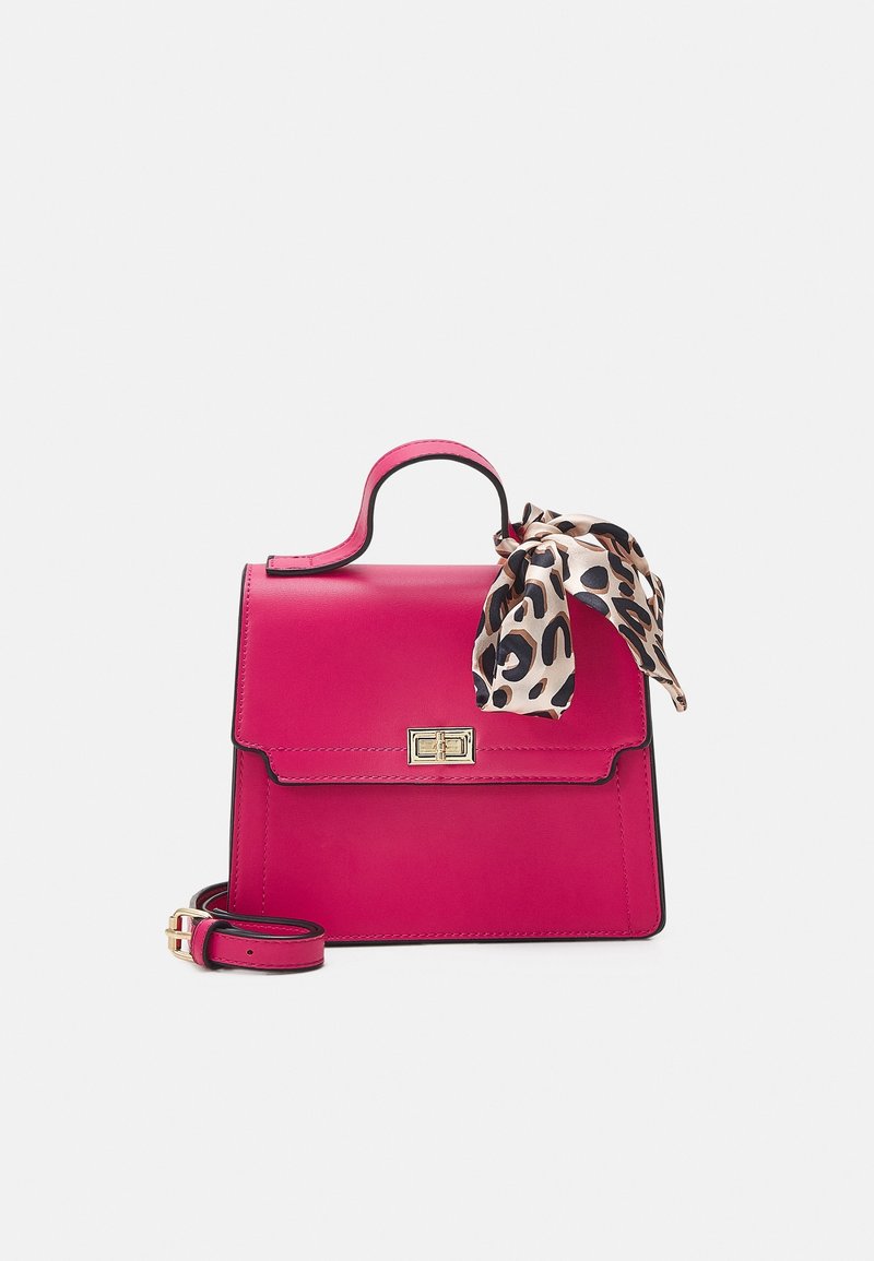 Ljusa rosa handväska med överhandtag, guldlås, avtagbar axelrem och en knuten leopardmönstrad scarf på handtaget mot vit bakgrund.