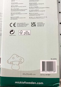 Embalaje del producto para un andador para bebés, con un fondo de color verde claro, una ilustración sencilla de un hongo y texto multilingüe que incluye advertencias de seguridad.