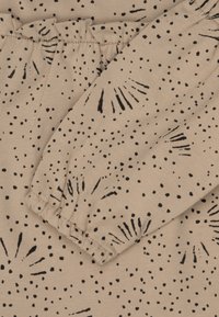 Tessuto di colore beige con motivo a macchie nere e disegni a esplosione. Presenta polsini elasticizzati e dettagli arricciati. Texture morbida, materiale elastico.